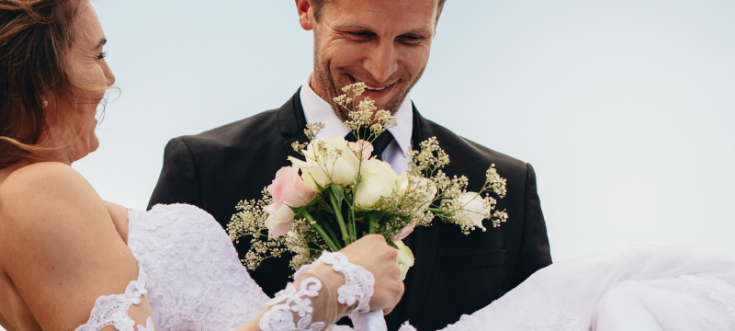 Bräutigam trägt seine Braut bei der Hochzeit über die Türschwelle – ein traditioneller Hochzeitsbrauch.