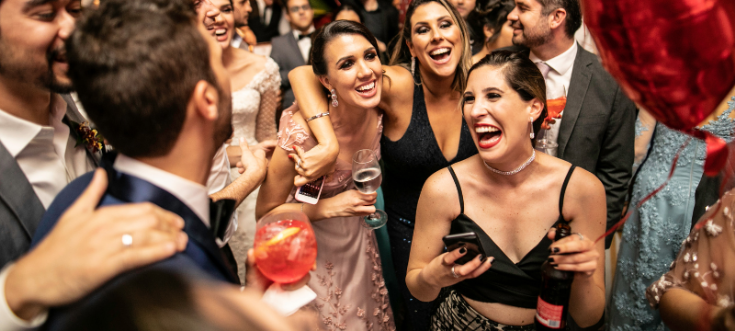 Gäste feiern ausgelassen auf einer Hochzeit mit DJ René – elegante Kleidung, Drinks und gute Laune.