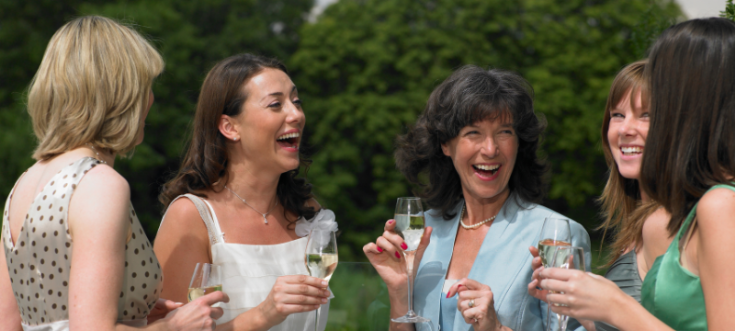 Fünf Frauen unterhalten sich lachend bei einer Hochzeitsfeier