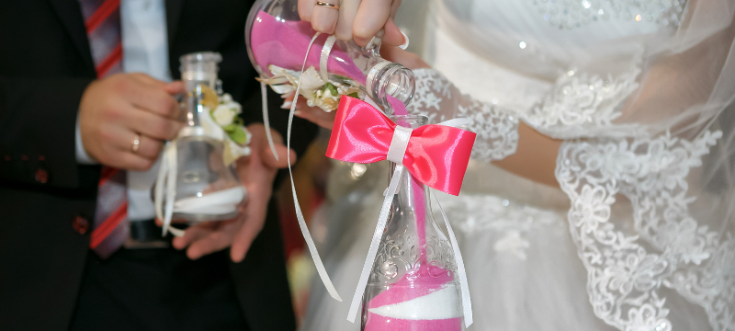 Sandzeremonie bei einer Hochzeit, bei der das Brautpaar verschiedenfarbigen Sand als Symbol für seine Verbundenheit zusammenführt.<br /> 