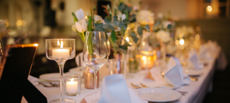 Elegante Tischdekoration mit weißen Servietten, Blumenarrangements und Kerzen für eine Hochzeitsfeier